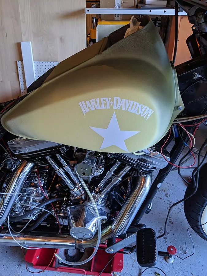 Positive stencil of Harley-Davidson text and a star applied to a motorcycle gas tank after spraying the darker green top coat