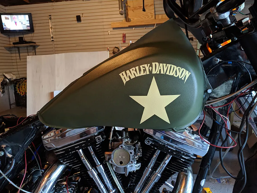 Finished motorcycle gas tank in olive green with the Harley-Davidson text and star showing in the pale yellow base color after the stencil was removed